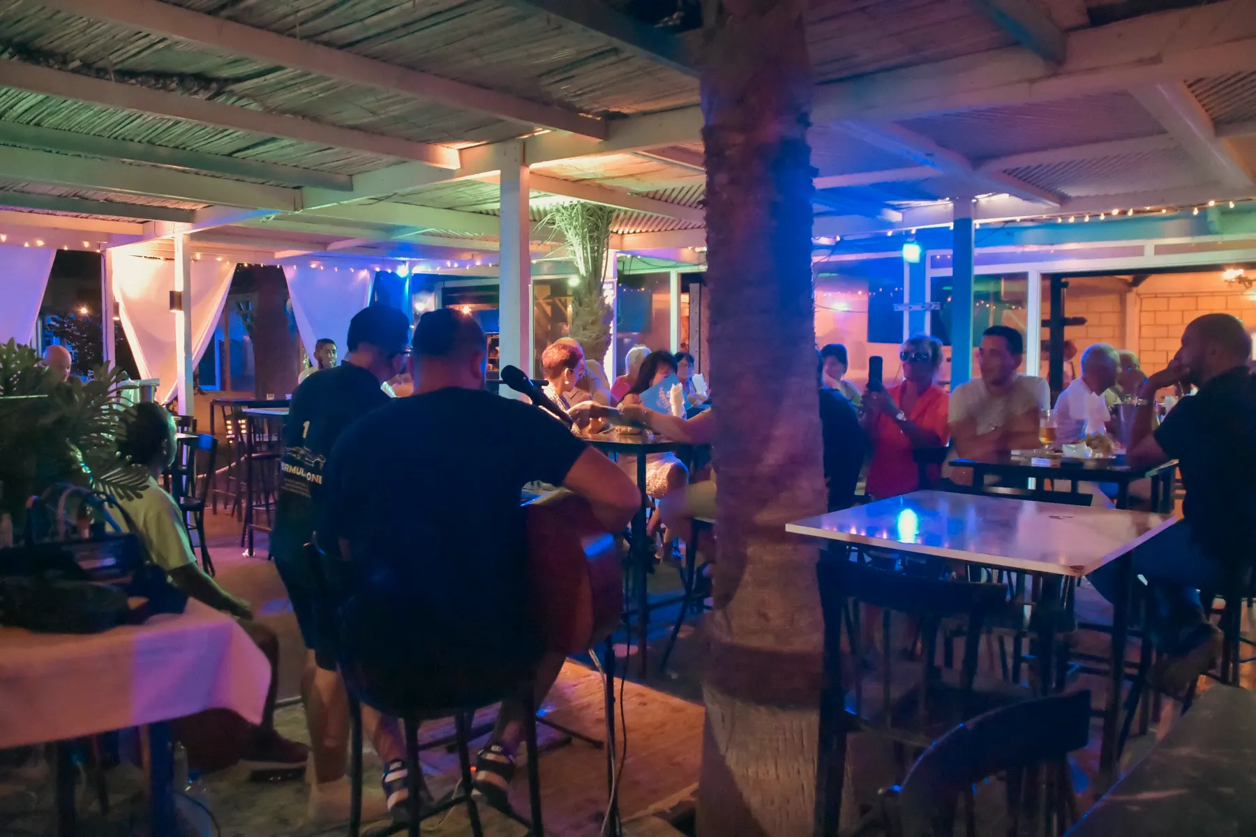 Soirée au beach bar de Dar El Bhar : hôtes attablés sous les lumières, au bord de la plage
