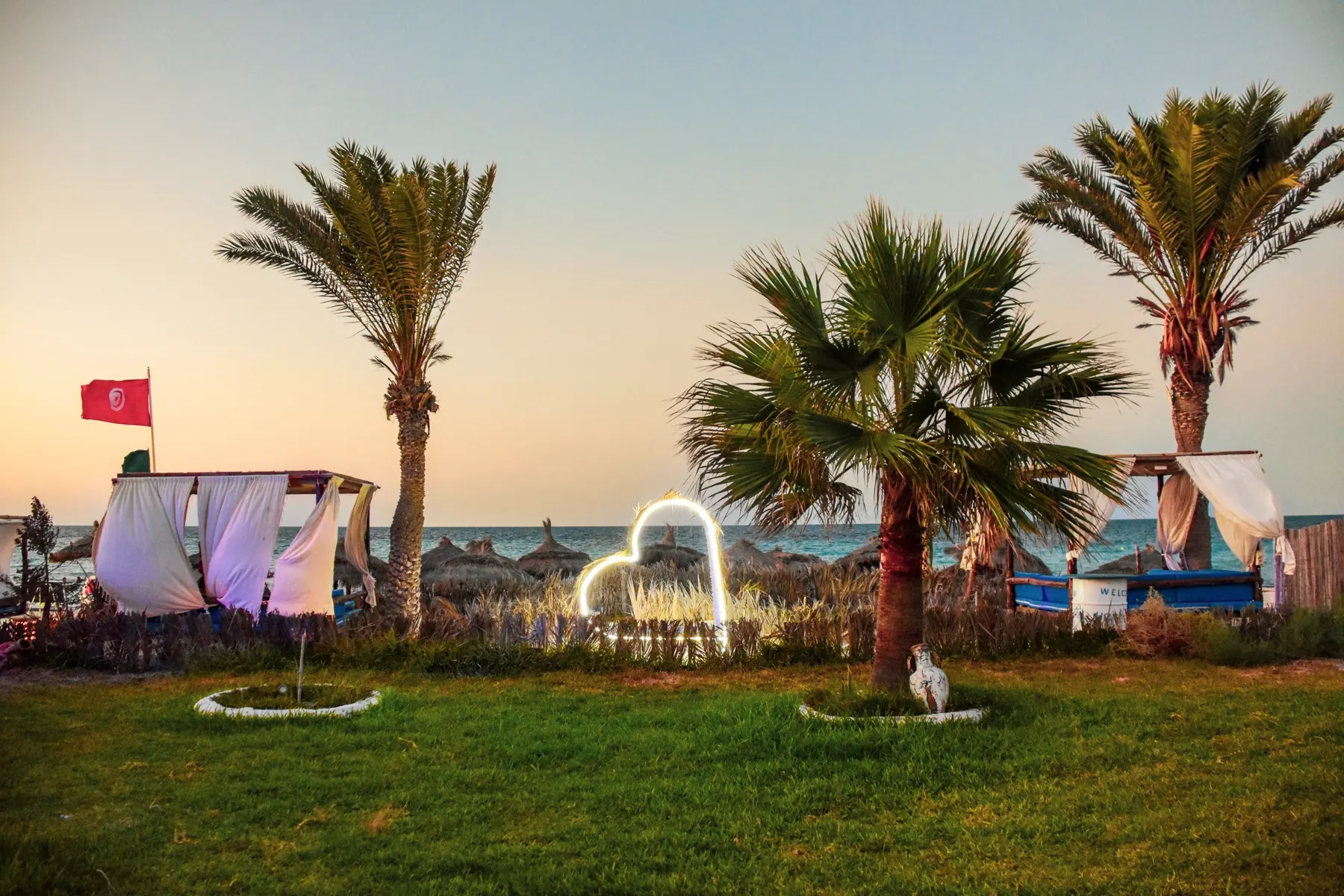 Le beach bar de Dar El Bhar au coucher du soleil : palmiers, lumières et ciel orangé